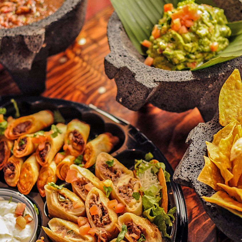 Party platter taquitos, mini quesadillas, chips, salsa and guacamole in stone molcajetes