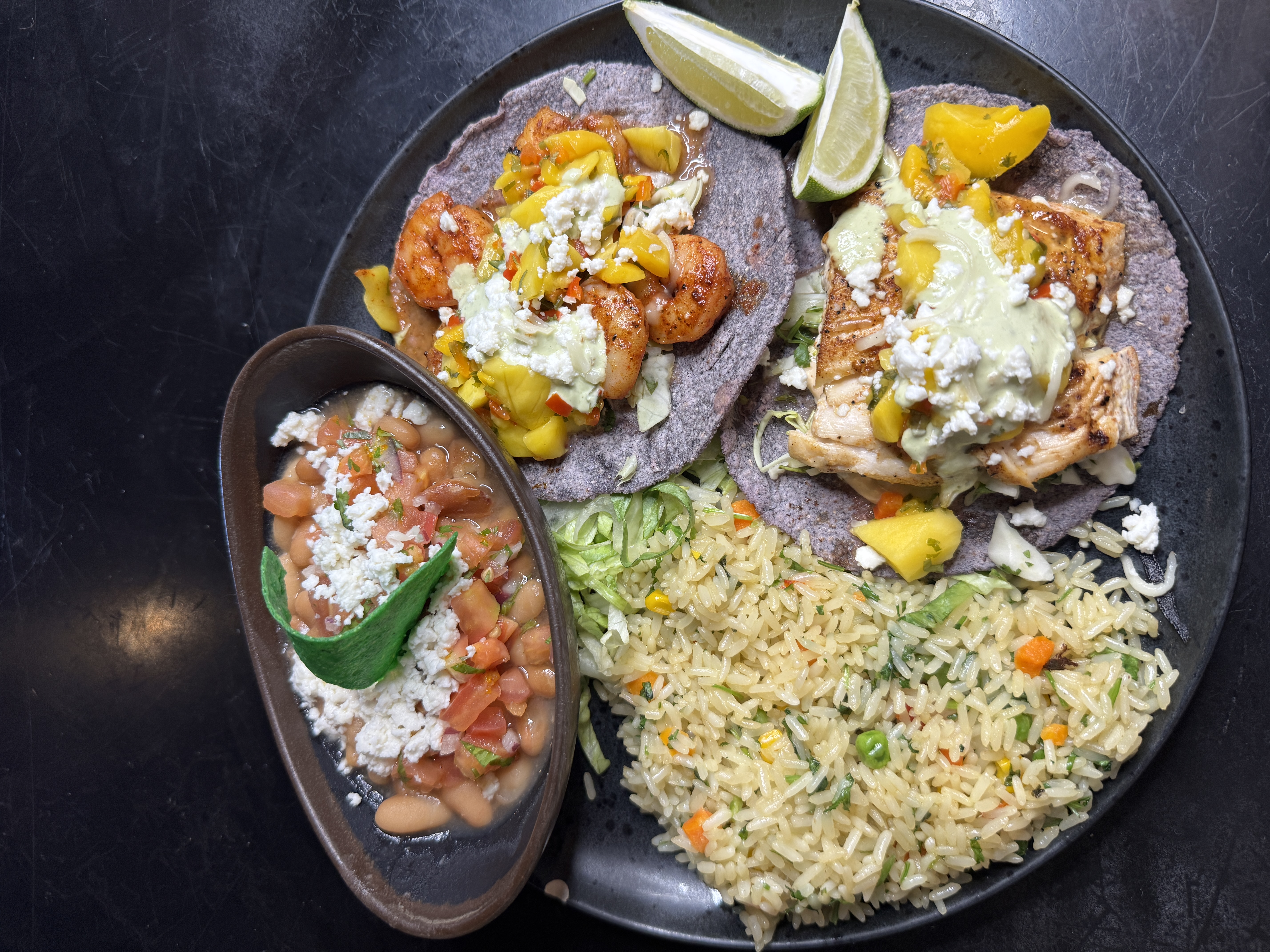 Grilled shrimp and fish tacos on blue-corn tortillas with mango salsa, rice and pot beans