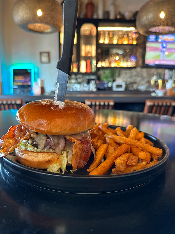Qué Pasa Spicy Burger with bacon and pepper jack on a brioche bun, sweet potato fries